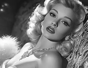 Glamorous woman in vintage 1950s attire, striking a pose in black & white